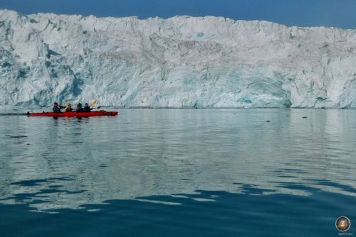 'n Kajak roei voor die indrukwekkende gletserrand van die Monaco-gletser in Svalbard