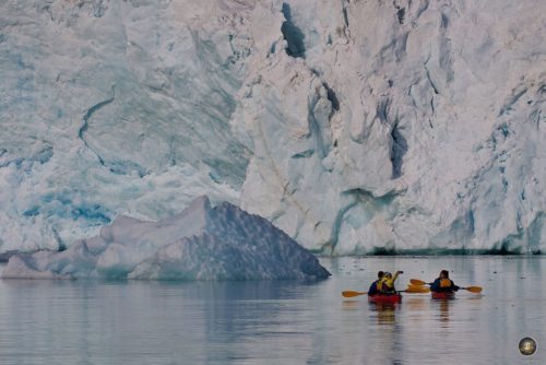 Duha ka kayaks sa atubangan sa usa ka bertikal nga yelo nga bungbong sa glacier sa usa ka biyahe ngadto sa Svalbard