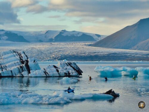 Kayaker trà iceberg cù strisce di frassini neri in Islanda nantu à u lavu glaciale Jökulsárlón in Islanda